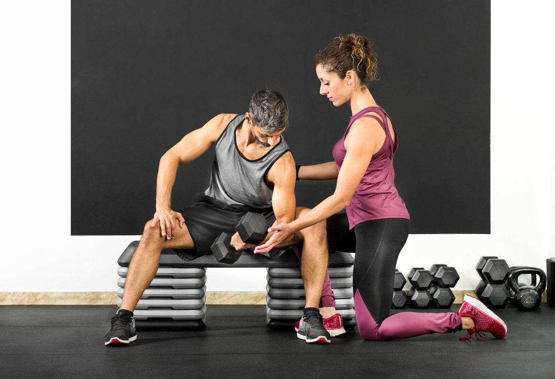 Female Fitness Trainer Helping a Man in a Gym