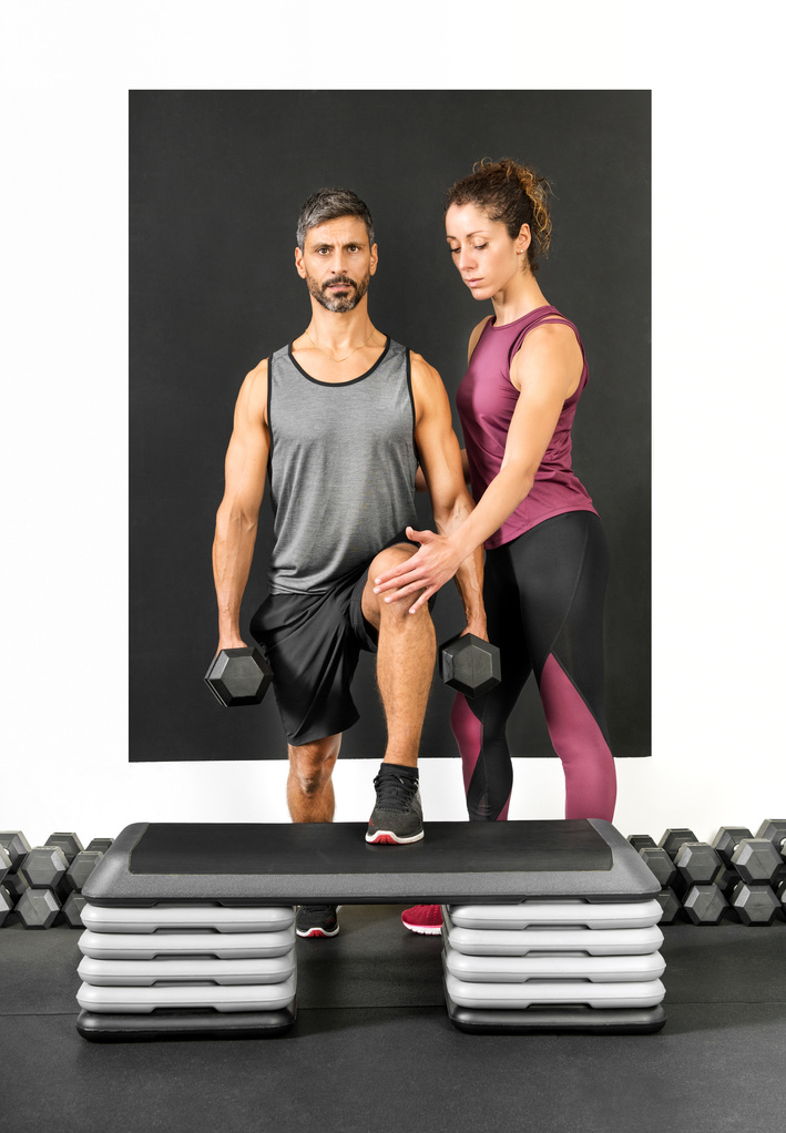 Female Personal Trainer Assisting a Man in a Gym